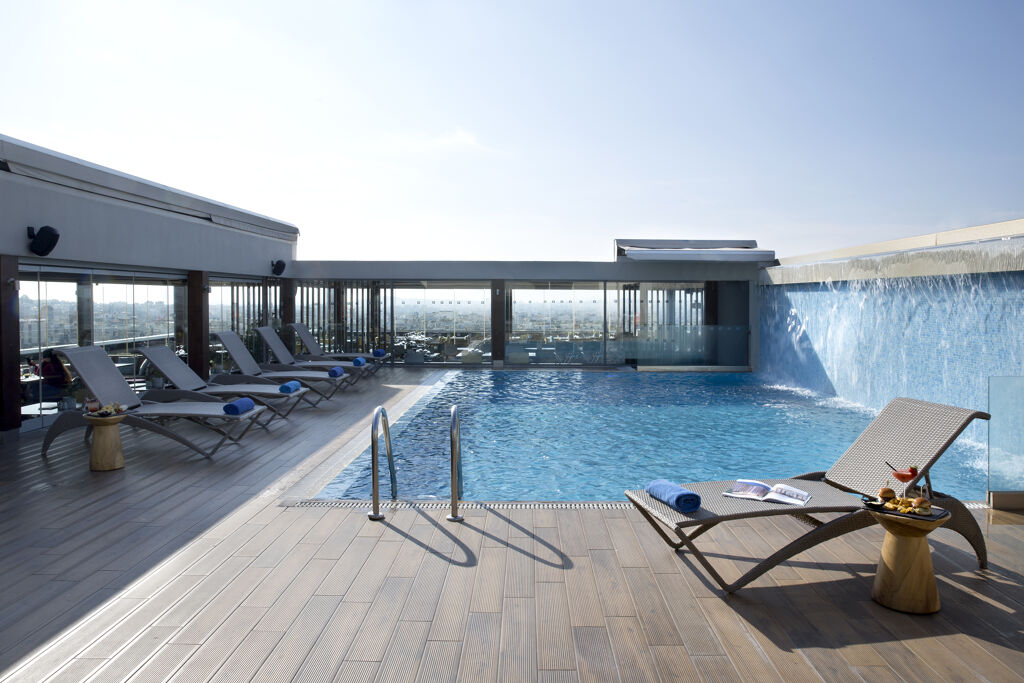 Piscine avec chaises longues de Wyndham Grand Athens Hôtel 5étoiles situé proche du centre d'Athènes capitale de la Grèce